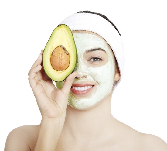 Young woman with facial mask and avocado