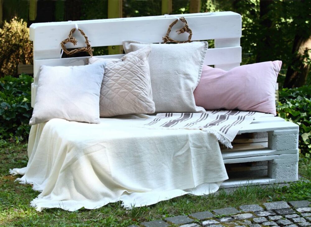 white painted pallet bench with pillows and blanket