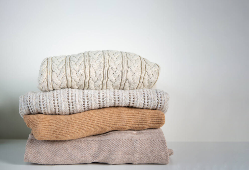 stack of knit sweaters in neutral colors
