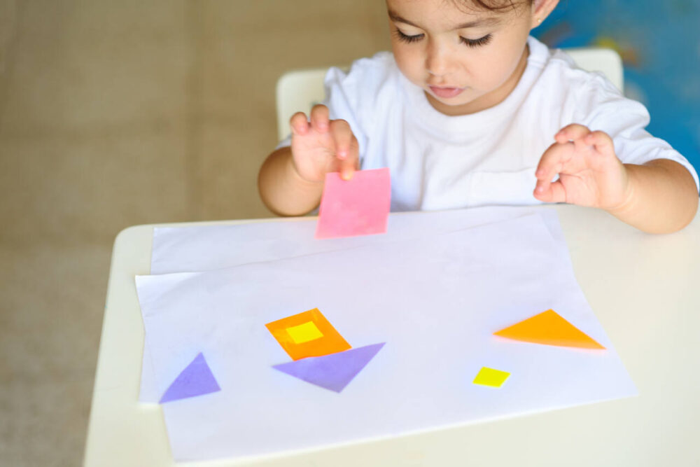 Little girl gluing shapes on paper