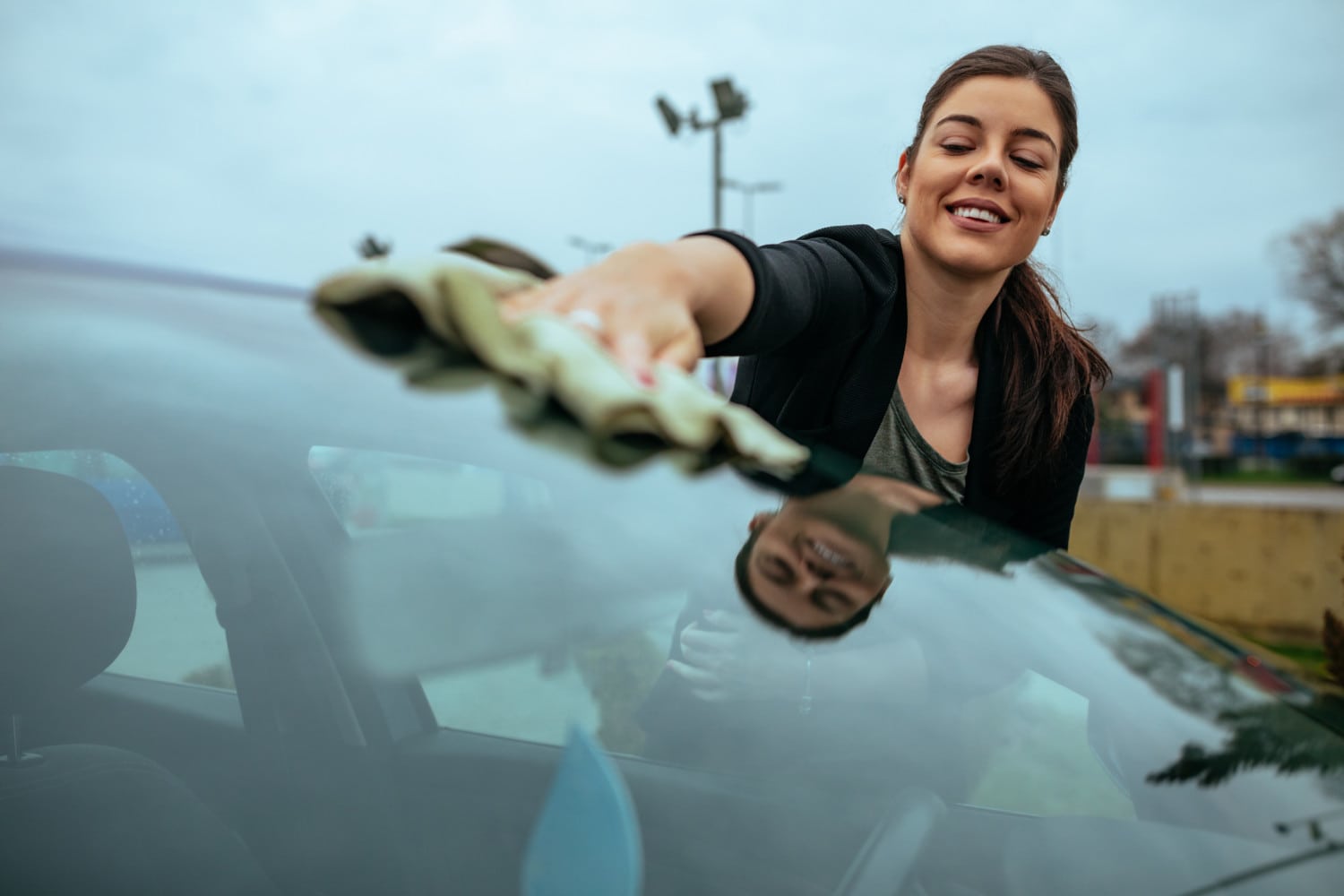 Shot of a young woman cleaning her car