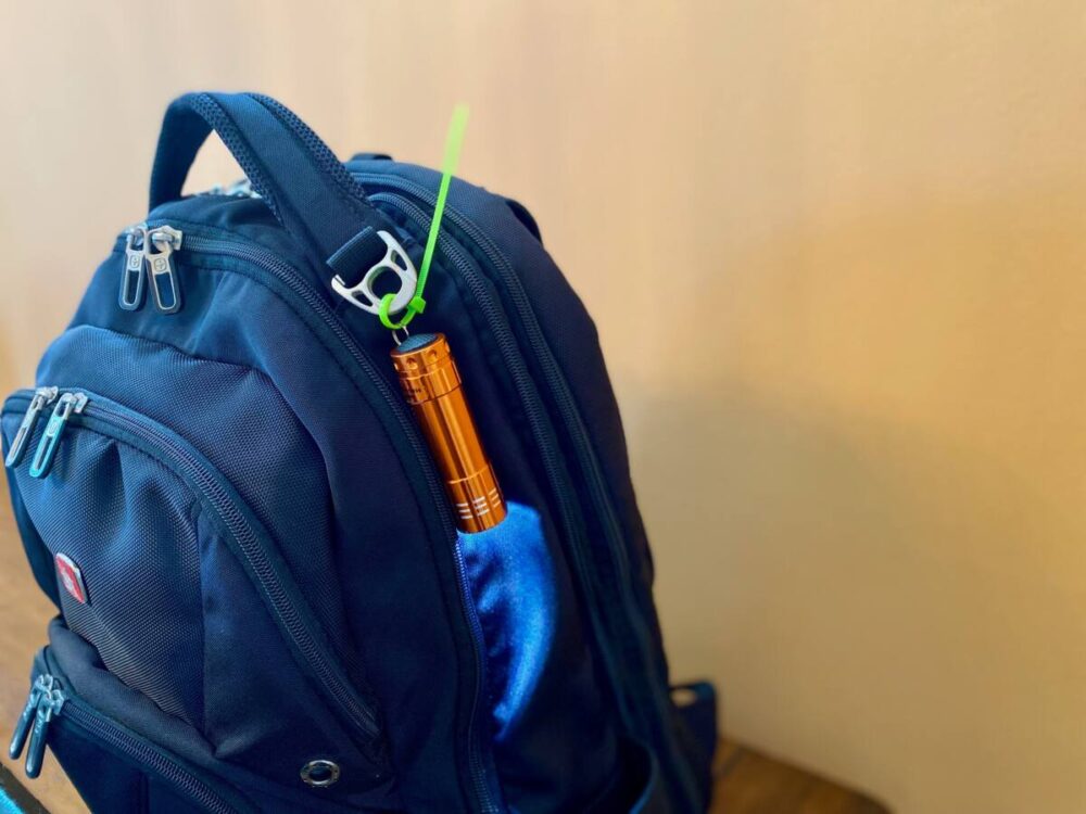zip tie secures a flashlight to backpack 