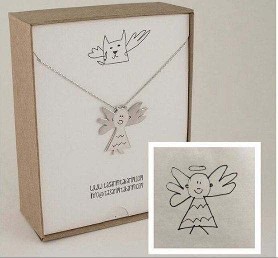 a silver angel necklace in a cardboard jewelry box