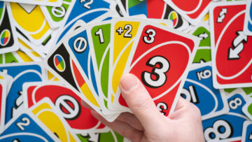 A person holds Uno cards are scattered cards.