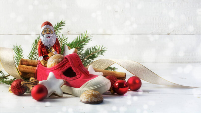 Children's red shoe filled with sweets, cookies and Christmas decorations for St. Nicholas Day on the December 6