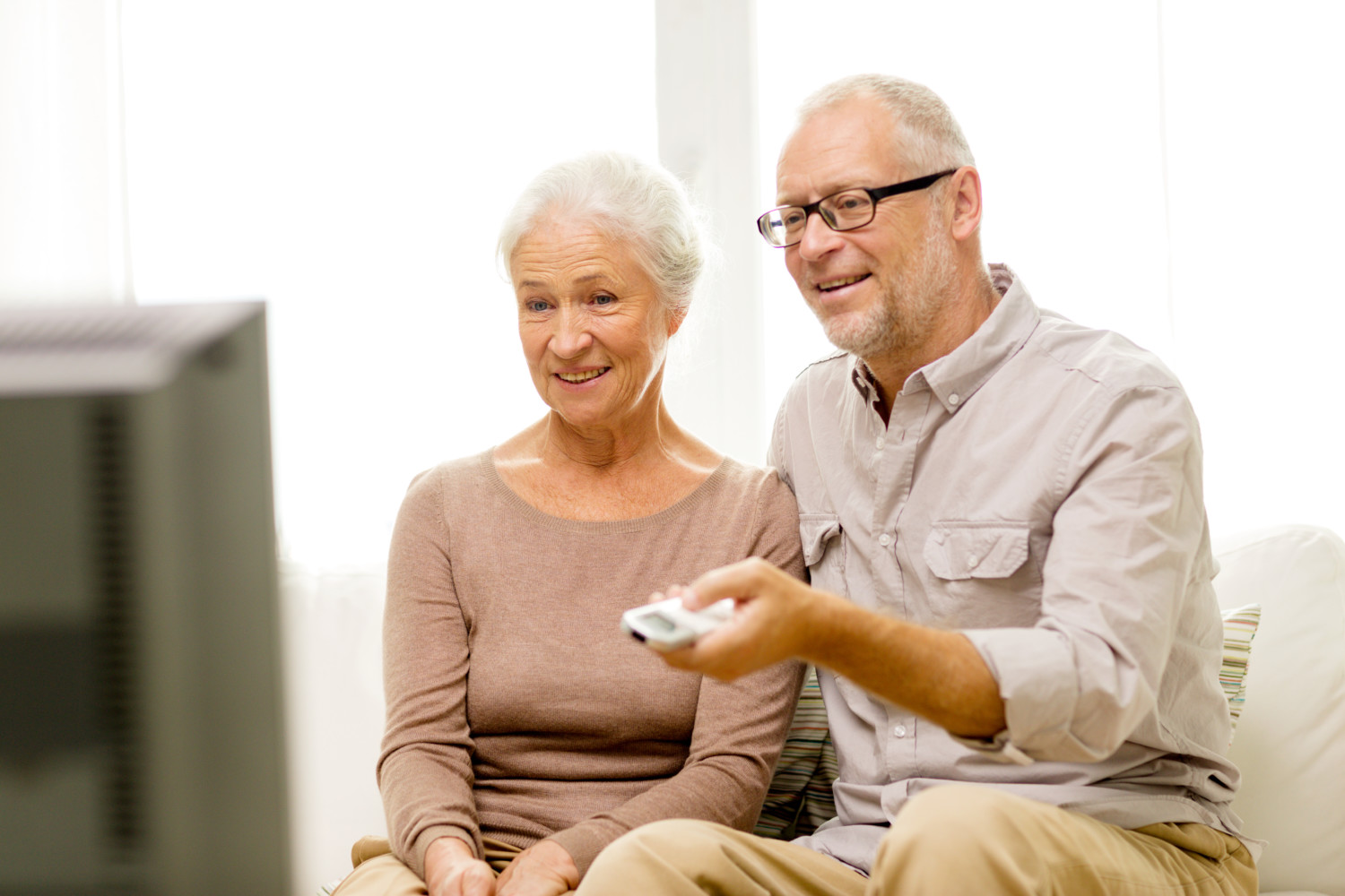 family, technology, age and people concept - happy senior couple watching tv at home