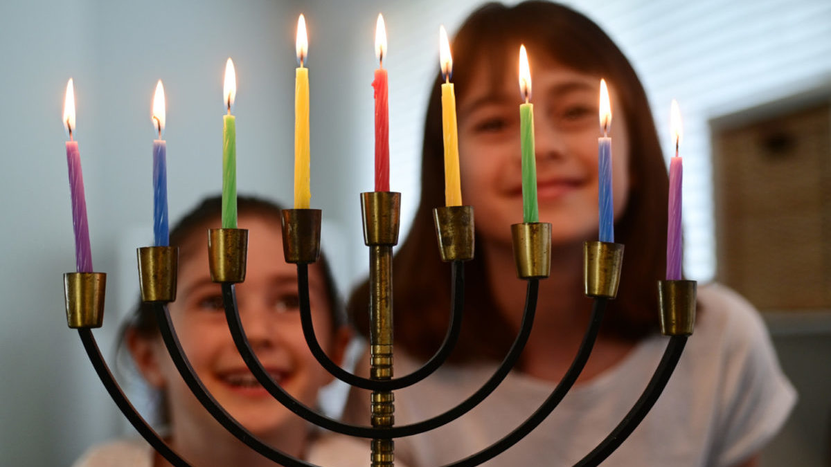 2 young girls happy on Hanukkah in front of menorah