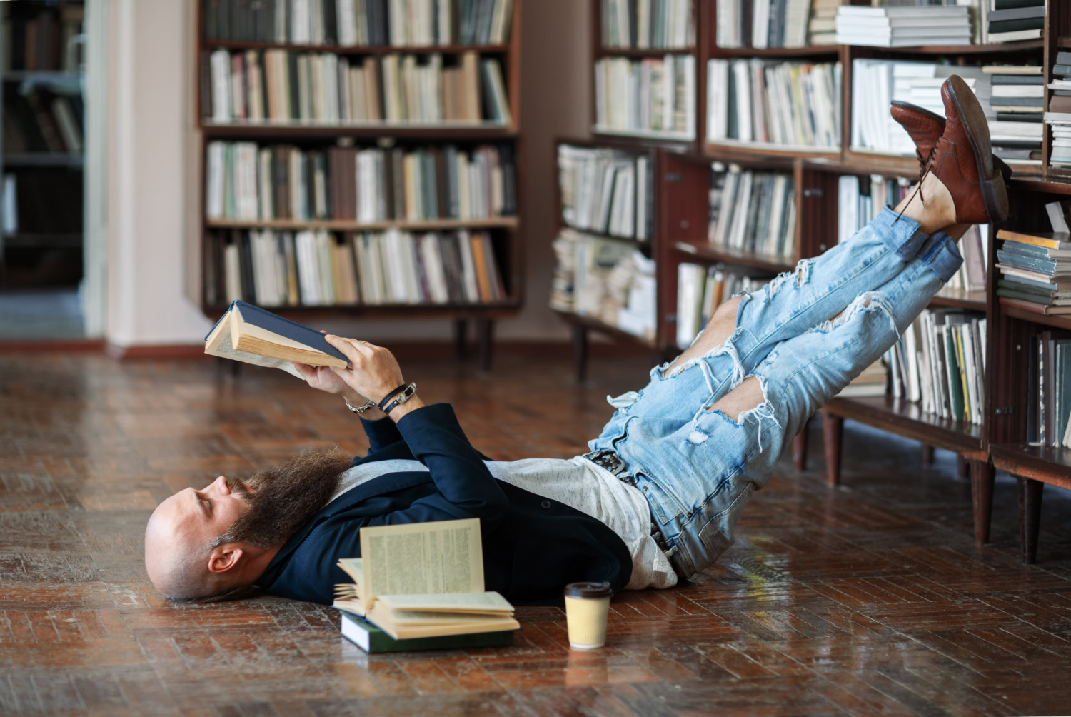 Man reads book on floor in library