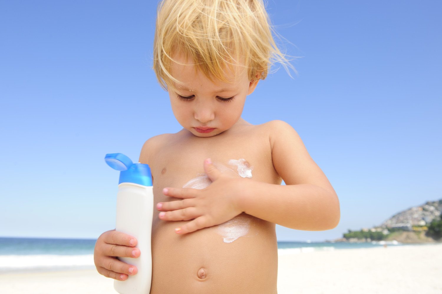 Child applying sunscreen at beach