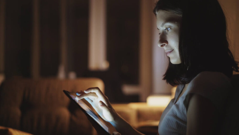 Woman reads on tablet at night