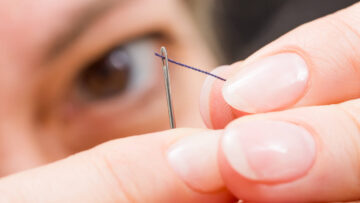 A woman threads a needle