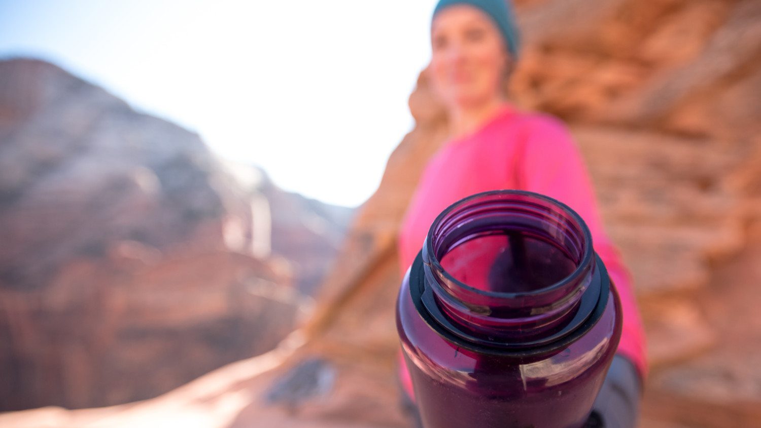 woman hiking and holding purple water bottle