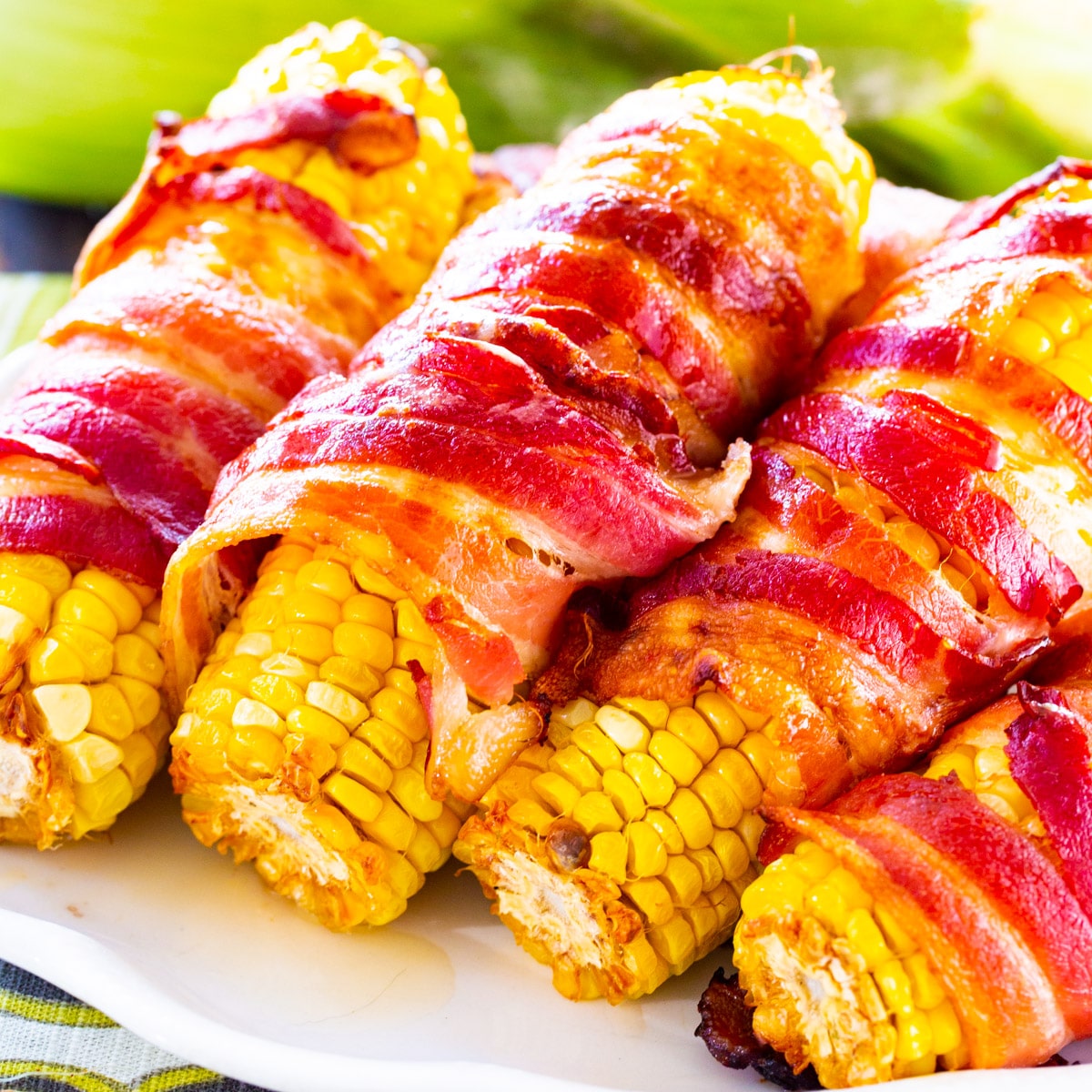 Spicy bacon-wrapped corn on white plate