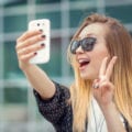 young woman taking a selfie with her fingers making a peace sign