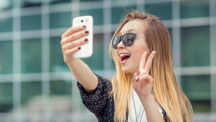 young woman taking a selfie with her fingers making a peace sign