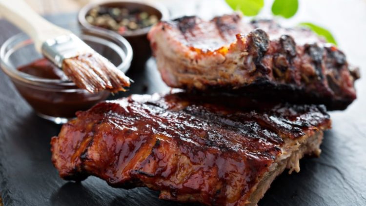 Oven-baked ribs on a plate with barbecue sauce.