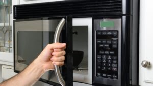 Hand opens microwave door