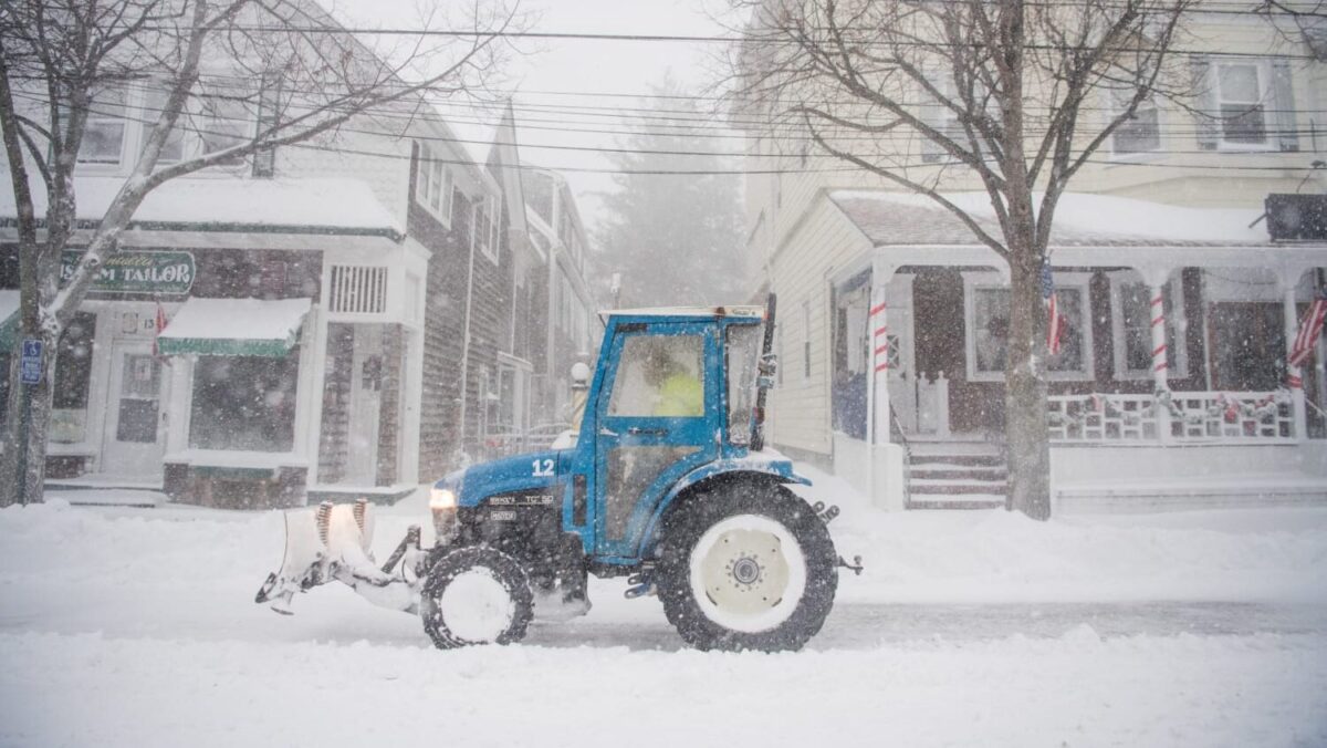 snow plow tractor in front of 2 houses