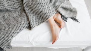 A woman's feet slipping out of a blanket on a comfy bed.