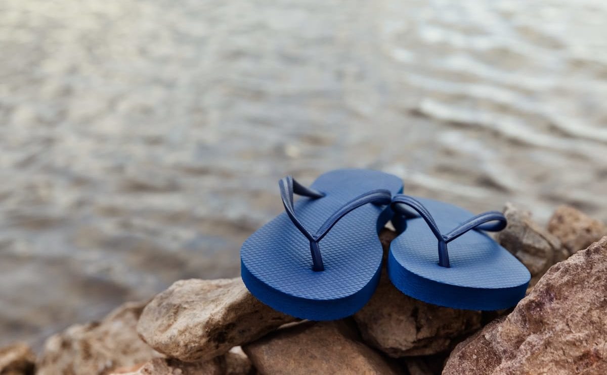 Closeup Of Blue Flip Flops On Rocky Beach At Summer Vacation