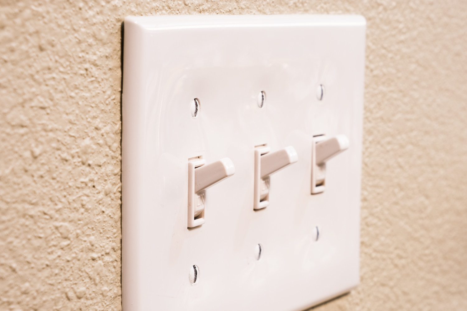 Traditional North American toggle white house electric light switch in ON position on aged old wood wall