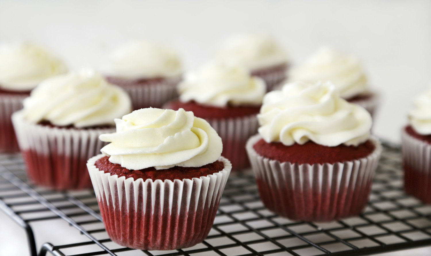 Red velvet cupcakes with cream cheese frosting on a rack