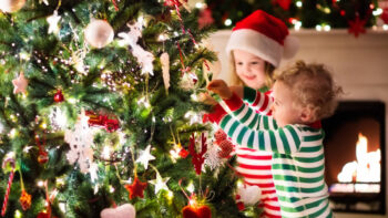 Cute kids in pajamas decorate Christmas tree