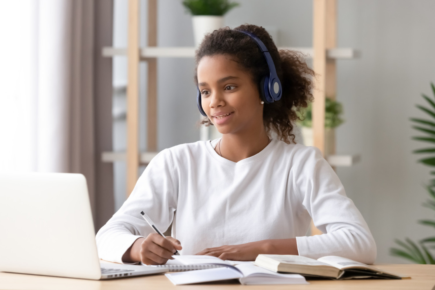 Black girl wearing headphones study with skype teacher on laptop