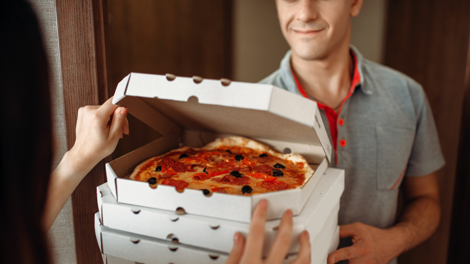 Delivery man shows pizza to customer at the door