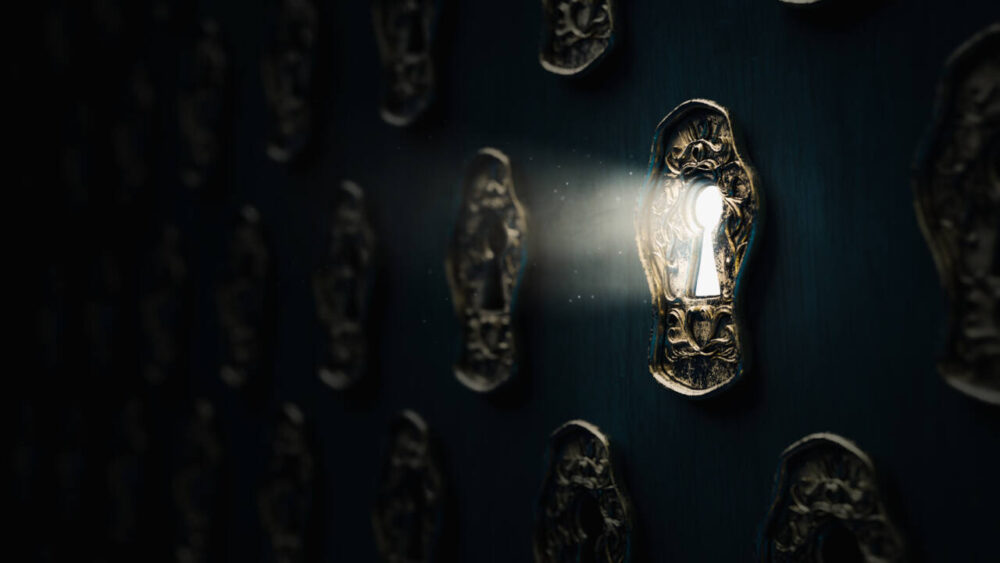 Light shines through a keyhole on a wall of keyholes