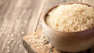 Uncooked rice in bowl on wood table