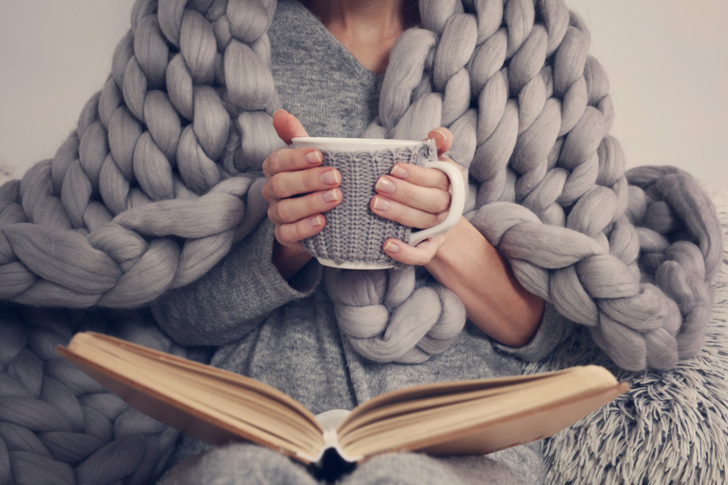 Woman holding mug while reading book