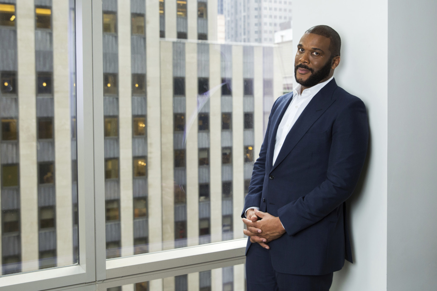 Tyler Perry stands in front of a window