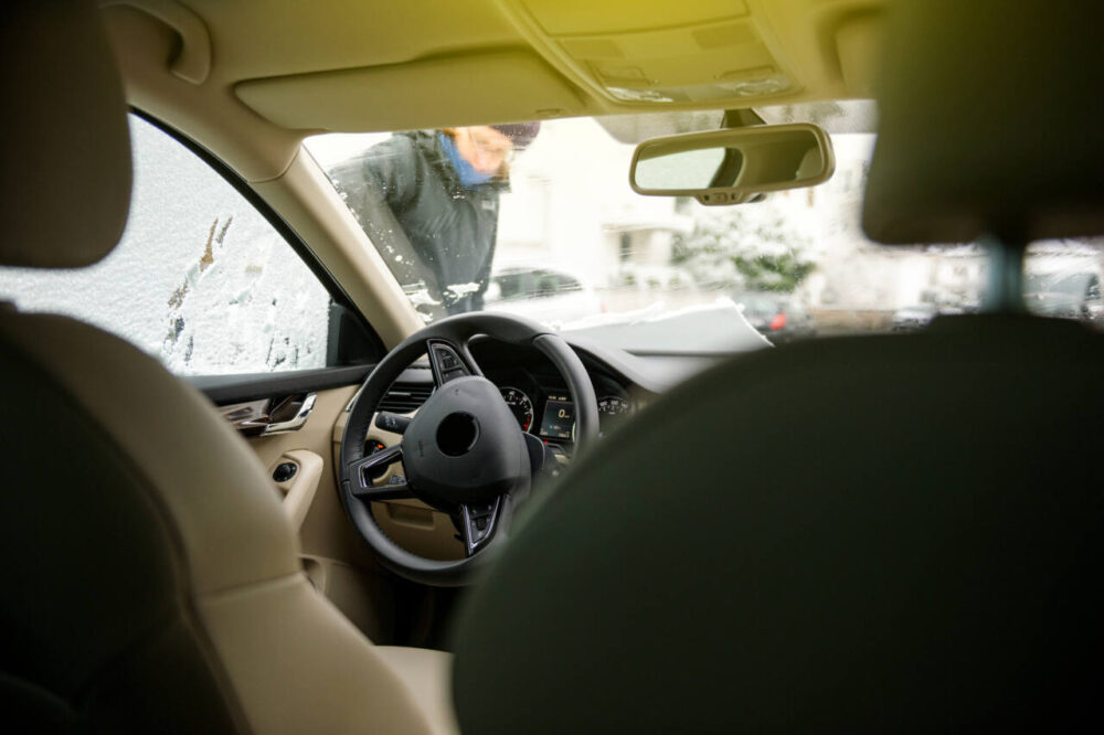 inside of car in winter with someone cleaning windshield