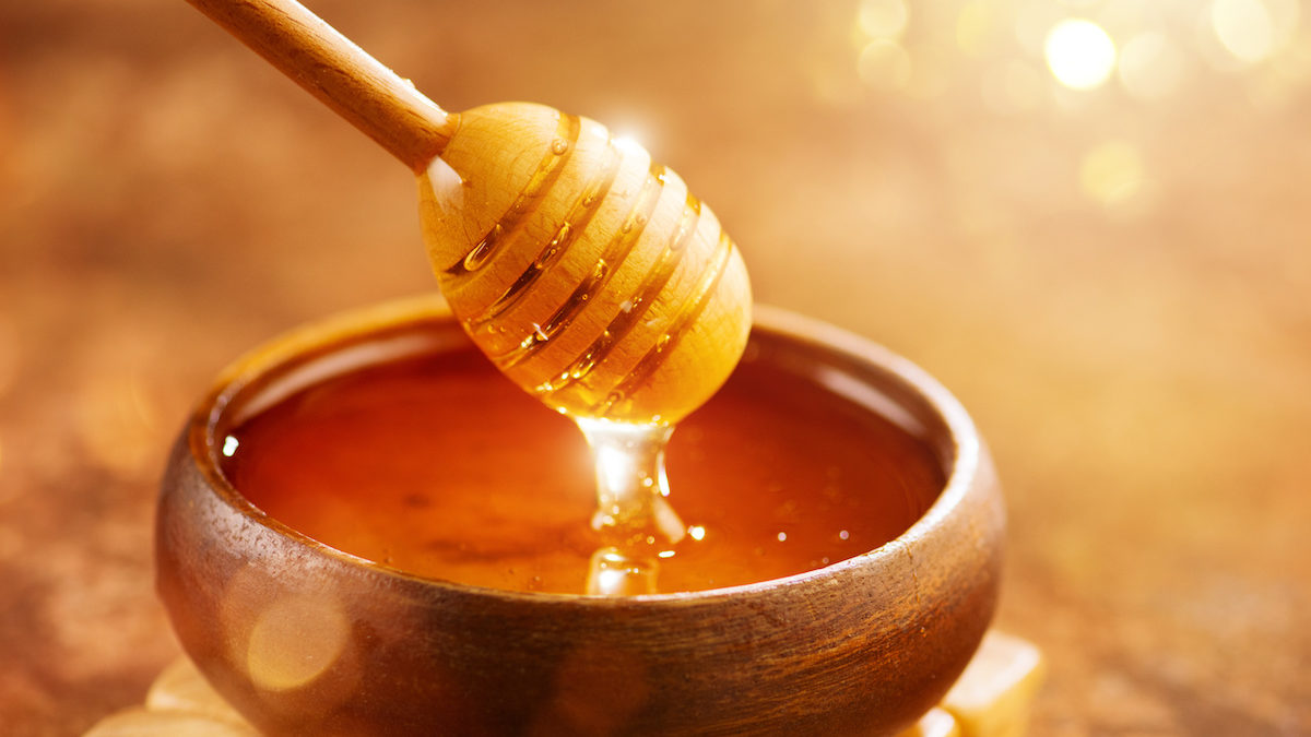 Honey with honey dipper in wooden bowl