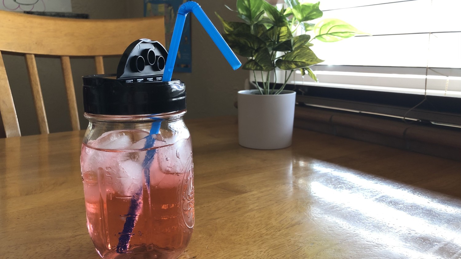 Pink drink in a Mason jar with straw and parmesan lid