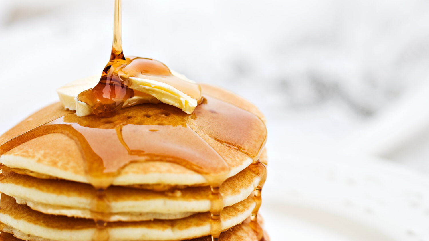 Maple syrup pouring onto pancakes