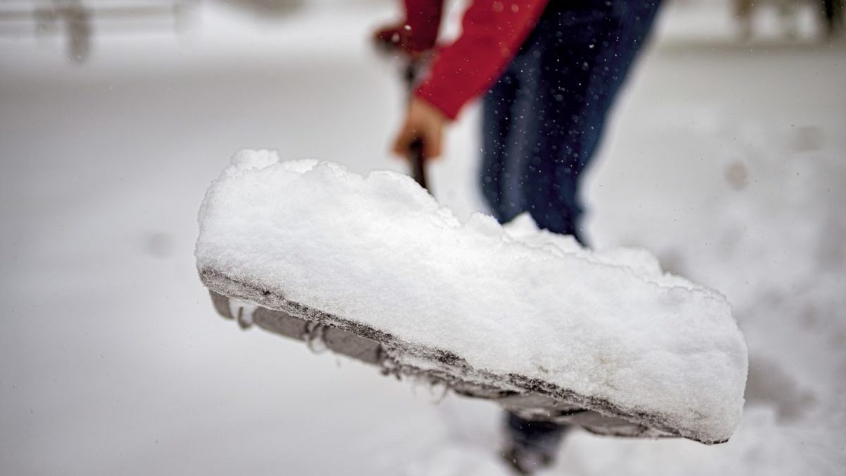 Shoveling snow away from house to prevent basement flooding