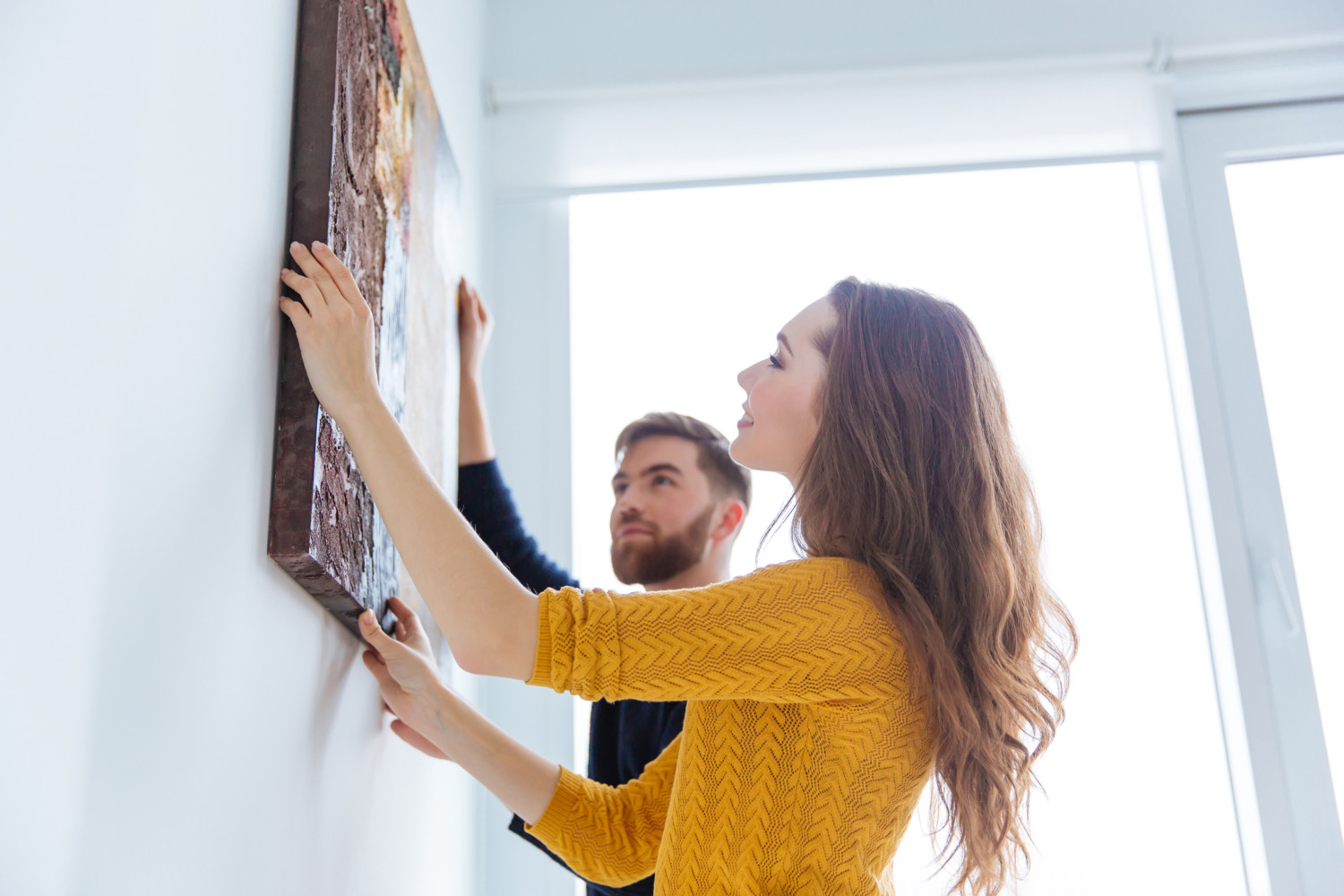 Couple hanging picture on wall
