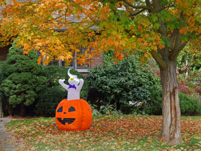 ghost and pumpkin on front lawn of house