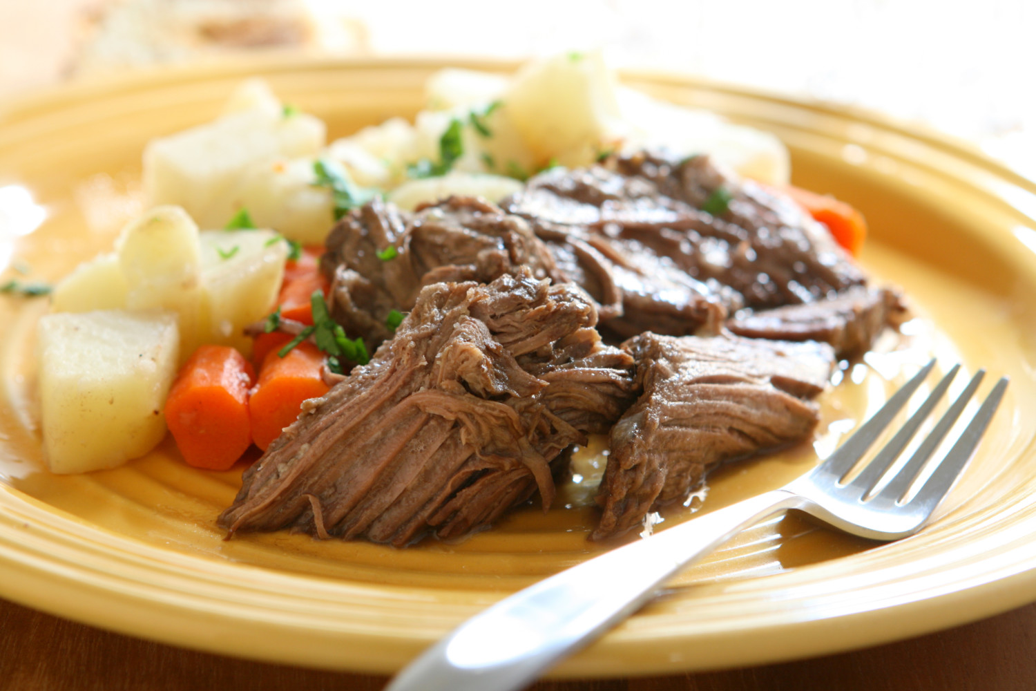 Pot roast on plate with carrots, potatoes