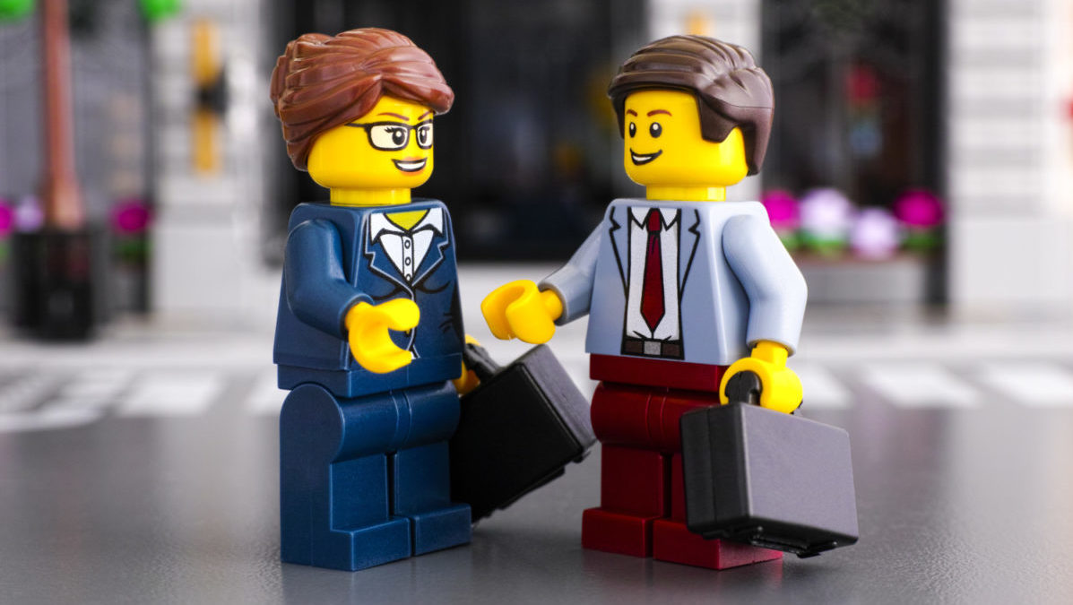 Lego minifigures shake hands, business man and woman with briefcases