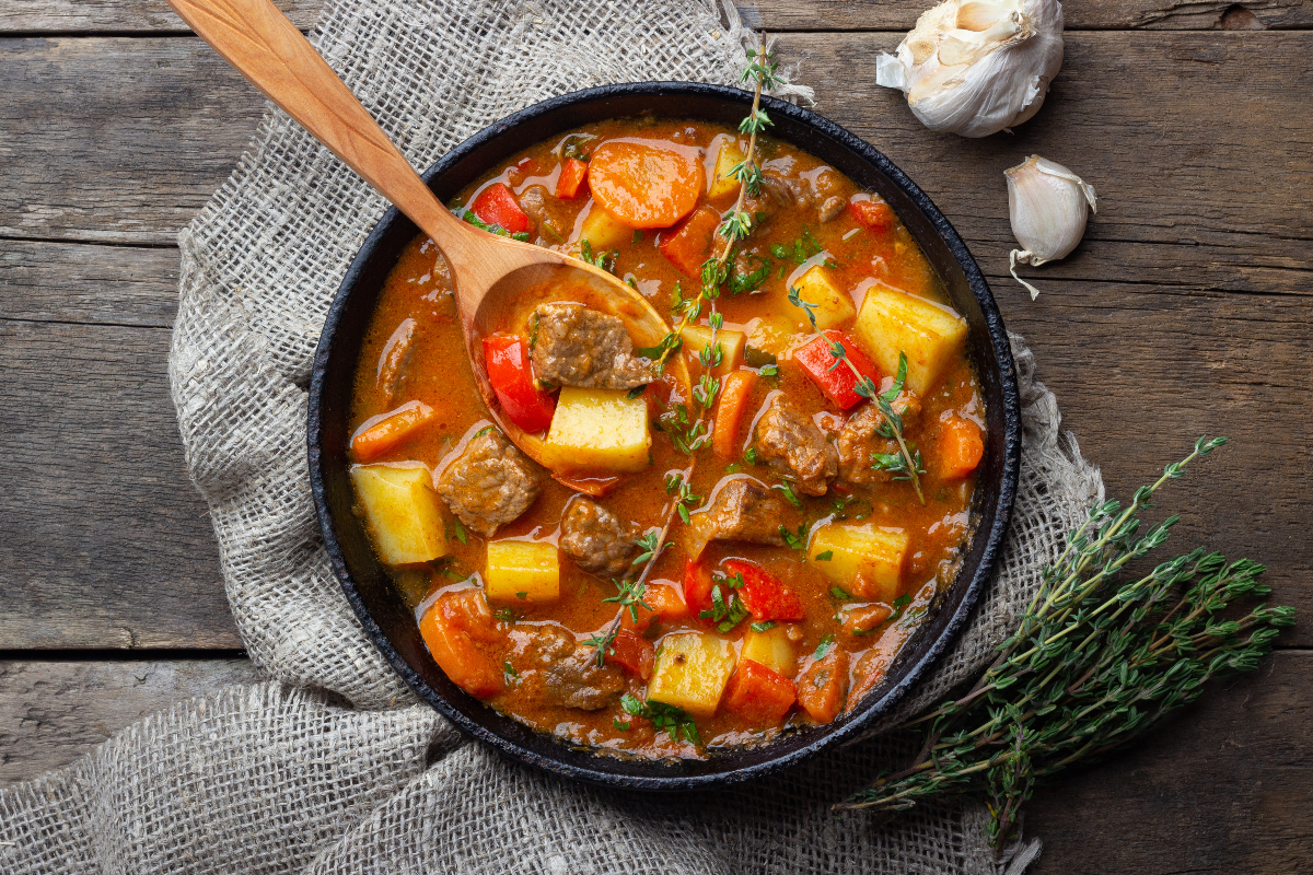 vegetable beef soup in pot with wooden spoon