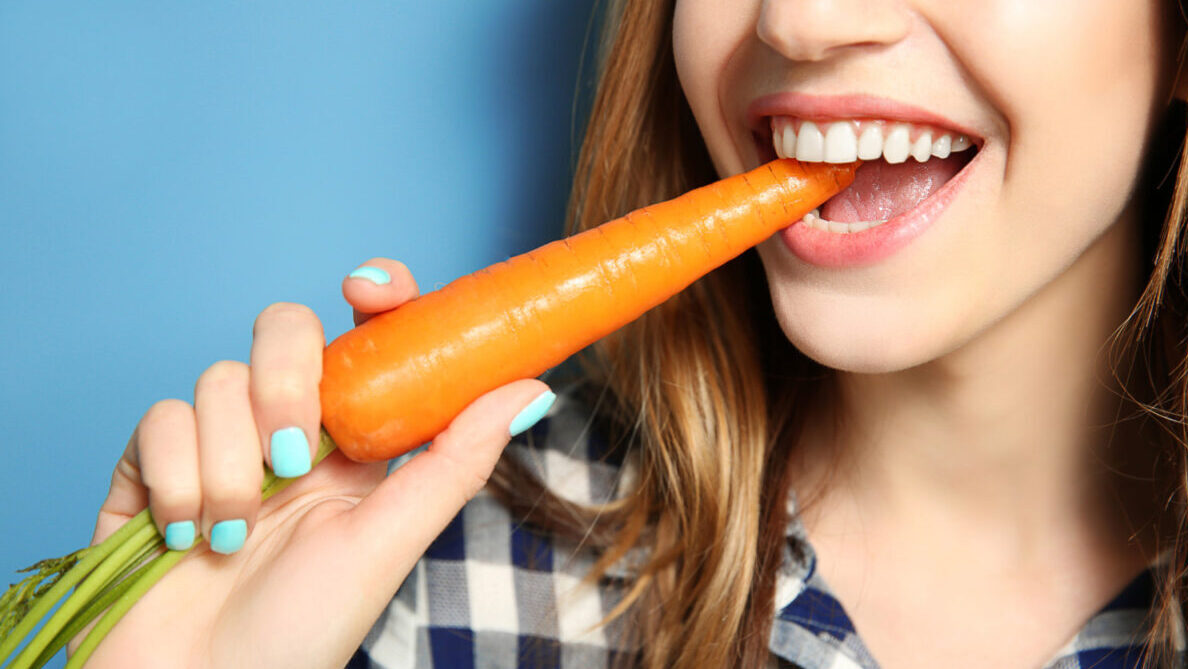 Woman bites into crunchy whole carrot