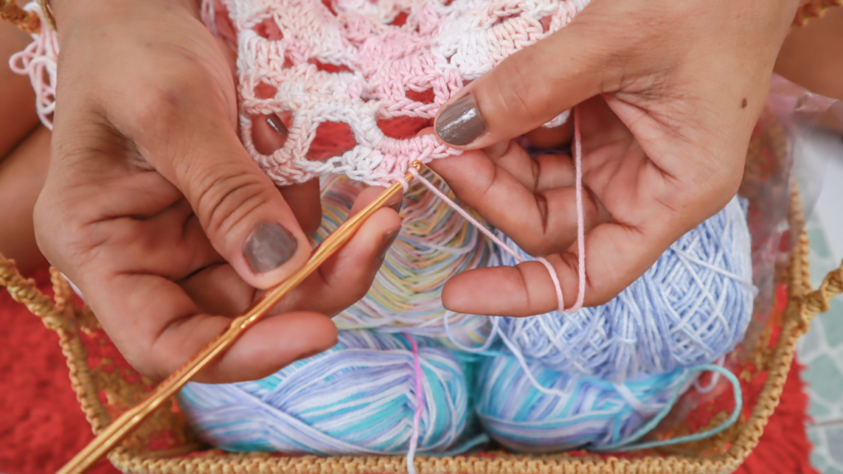 A woman's hands crocheting with colorful yarn.