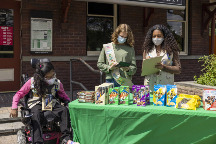 Girl Scouts selling cookies at a table