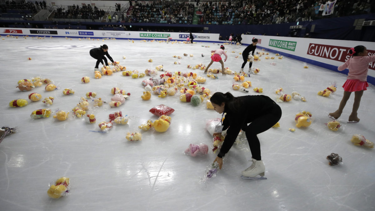 Crews clean stuffed animals off the ice after a figure skating performance by Yuzuru Hanyu.