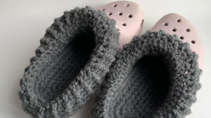 A pair of fuzzy crocheted liners are shown inside a pair of Crocs shoes.