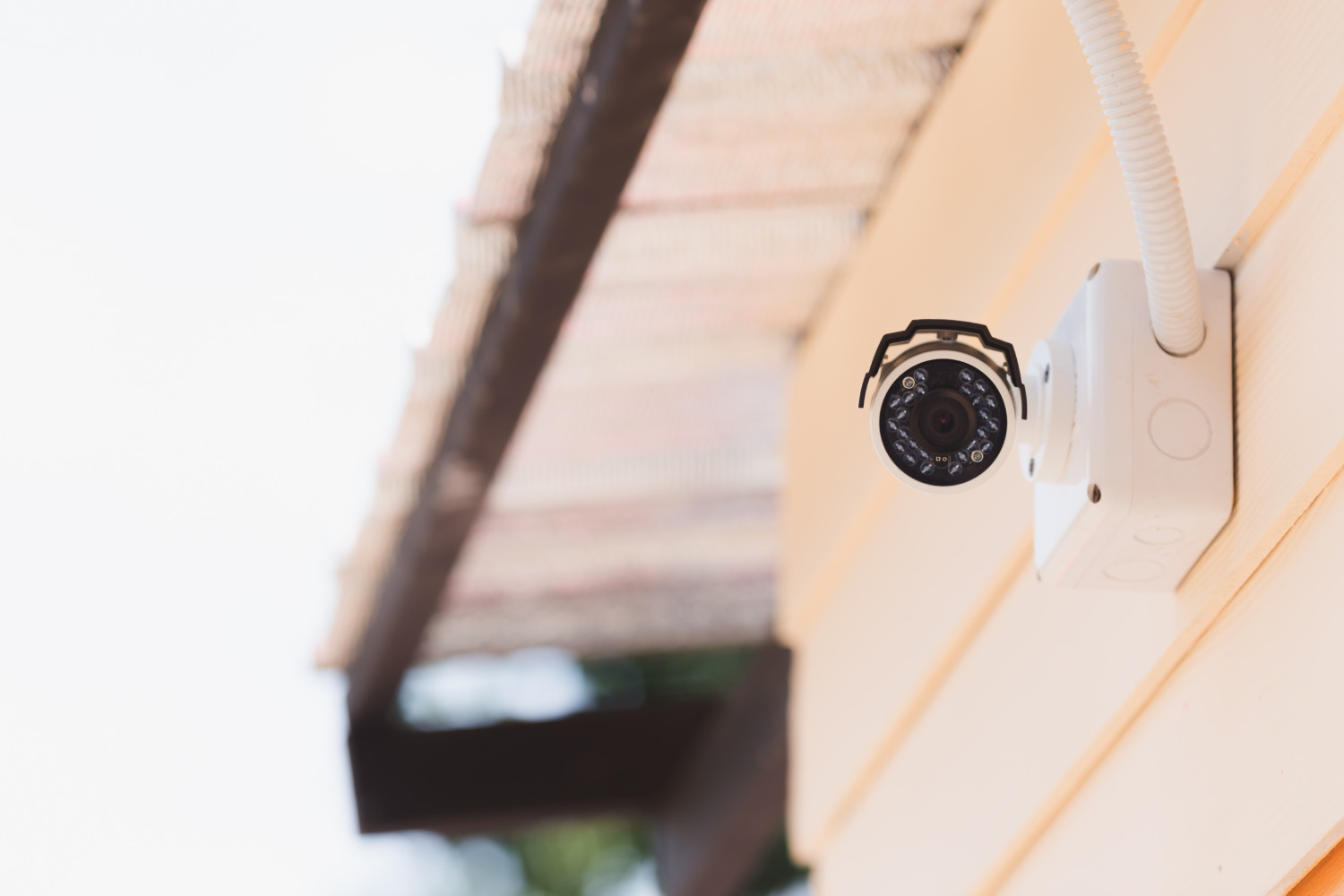 Digital security camera mounted to outside of yellow house