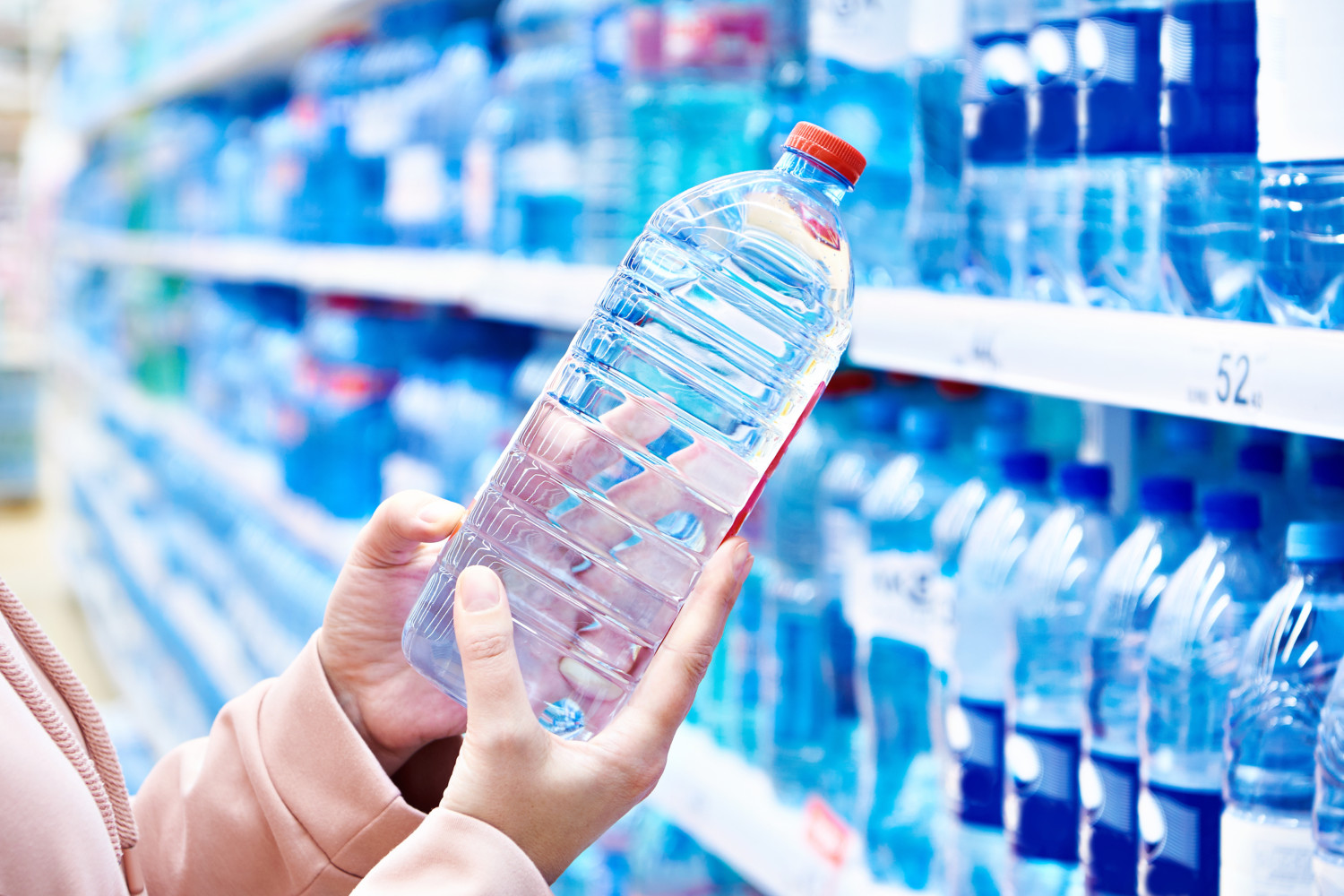 Shopper holds plastic bottle drinking water in store